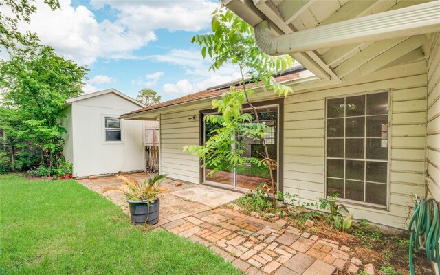 back of house with a lawn, an outdoor structure, a storage unit, and a patio area