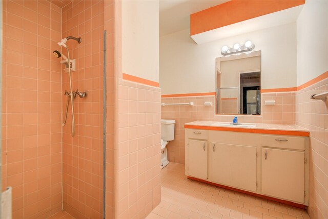 full bathroom featuring wainscoting, vanity, tile walls, a tile shower, and tile patterned flooring
