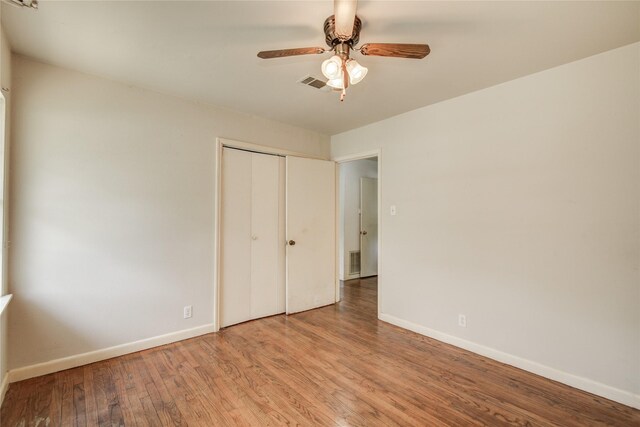 unfurnished bedroom featuring baseboards, wood finished floors, visible vents, and a closet