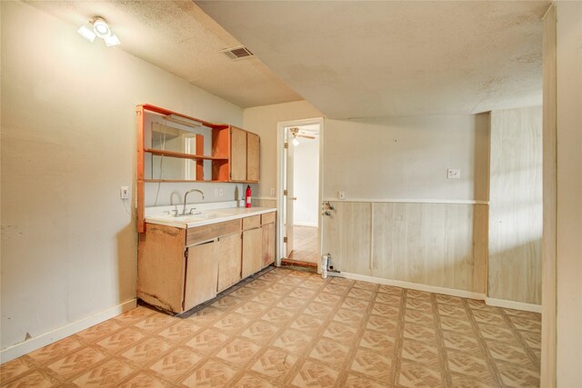 kitchen featuring a sink, a textured ceiling, visible vents, light floors, and light countertops