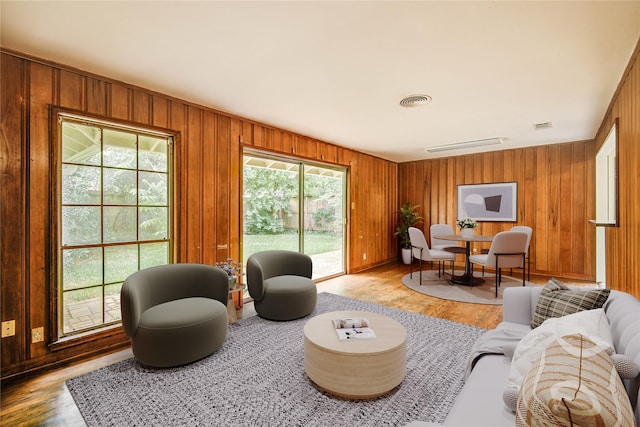 living area featuring wood walls, a healthy amount of sunlight, and light wood finished floors