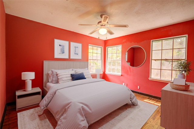 bedroom with baseboards, wood finished floors, ceiling fan, and multiple windows
