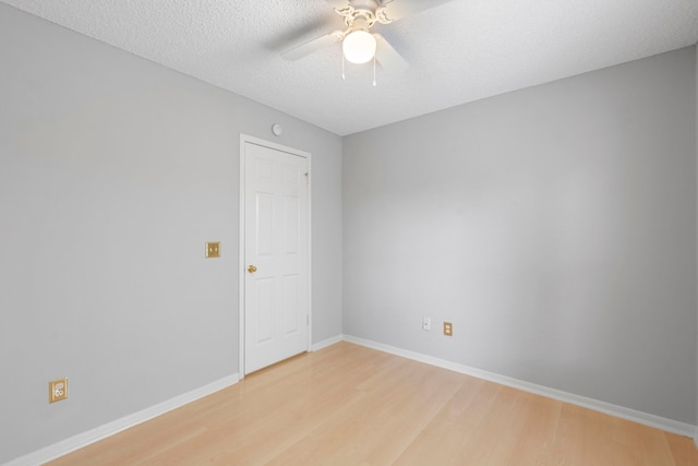 spare room featuring baseboards, a ceiling fan, a textured ceiling, and light wood-type flooring