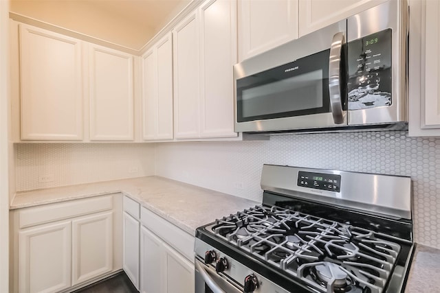 19622 Upper Canyon Ct, Cypress, TX 77433 - kitchen featuring white cabinetry, backsplash, appliances with stainless steel finishes, and light stone counters