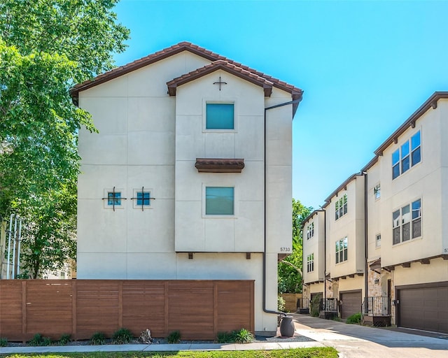 view of front of house featuring fence, stucco siding, and a tile roof