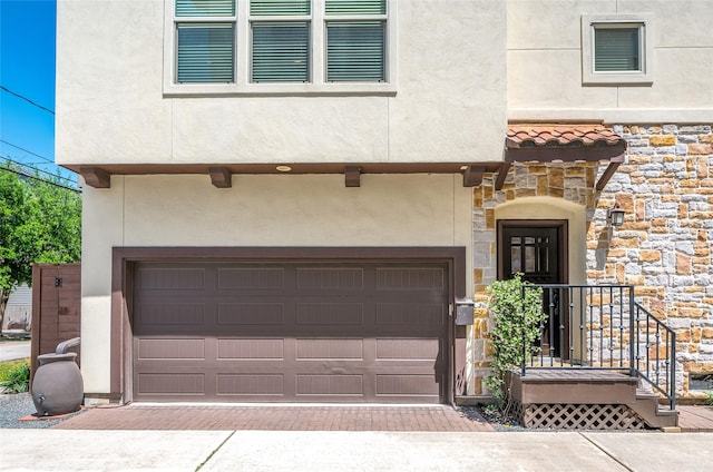 view of front of home featuring an attached garage, decorative driveway, stucco siding, and stone siding