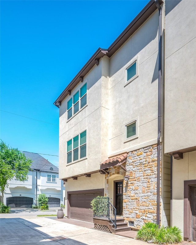 view of front of house with a garage, stucco siding, and stone siding