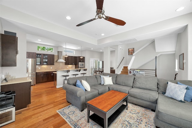 living area with recessed lighting, a ceiling fan, light wood-style flooring, and stairway