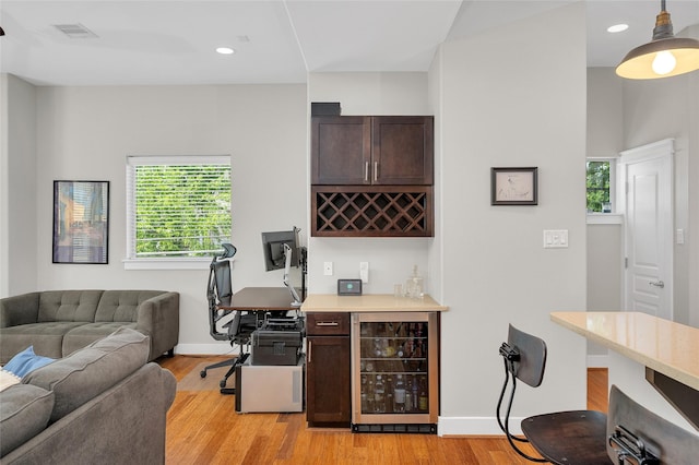 bar with a dry bar, light wood-style floors, beverage cooler, visible vents, and pendant lighting