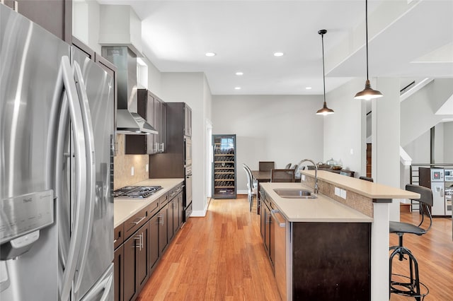 kitchen with wall chimney range hood, a sink, a kitchen breakfast bar, stainless steel appliances, and decorative backsplash