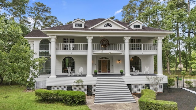 rear view of house with a porch, fence, a shingled roof, stairway, and a balcony