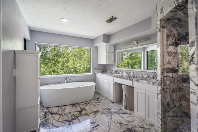 full bath featuring plenty of natural light, visible vents, a textured ceiling, and double vanity