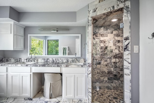 bathroom featuring marble finish floor, a sink, a shower stall, and double vanity
