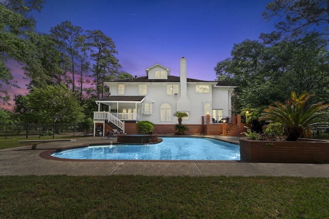 back of house with stairway, a chimney, an outdoor pool, fence, and a wooden deck
