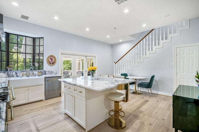 kitchen featuring dishwasher, white cabinets, a healthy amount of sunlight, and light wood-type flooring