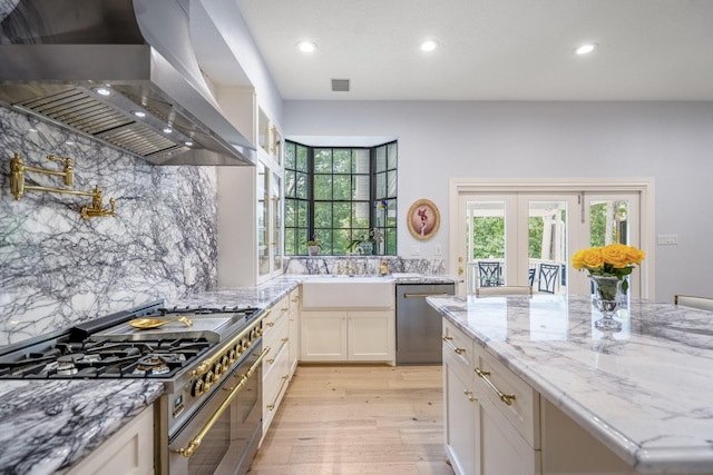 kitchen featuring decorative backsplash, stainless steel appliances, light wood finished floors, wall chimney exhaust hood, and recessed lighting