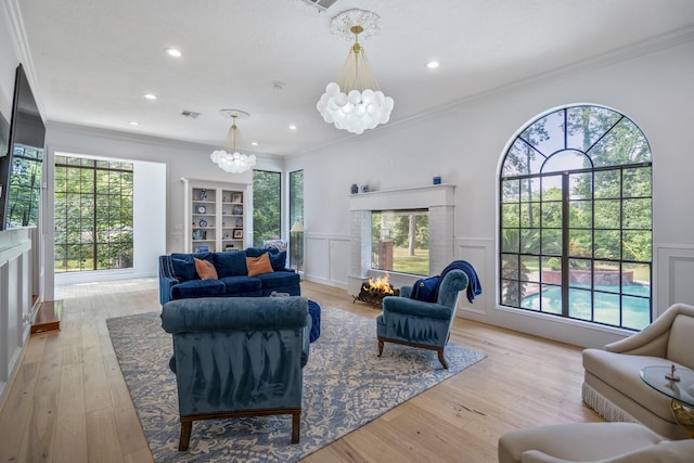 living area with recessed lighting, an inviting chandelier, visible vents, a decorative wall, and wainscoting