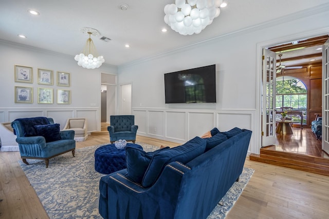 17003 Creeksouth Rd, Houston, TX 77068 - living area featuring a chandelier, a decorative wall, light wood-style floors, crown molding, and a wainscoted wall