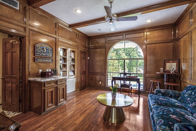 living room with a textured ceiling, a decorative wall, and dark wood-style floors