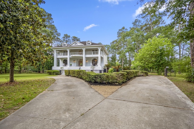 neoclassical / greek revival house with a porch, driveway, and a front yard