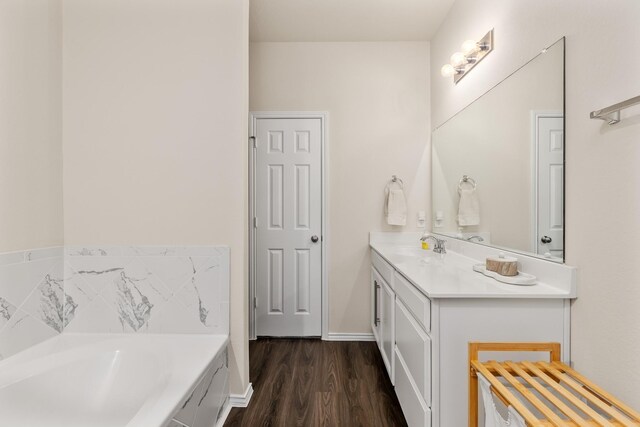 bathroom featuring vanity, wood finished floors, a garden tub, and baseboards