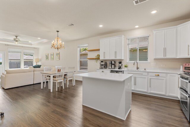 kitchen with a sink, stainless steel appliances, white cabinets, light countertops, and dark wood-style floors