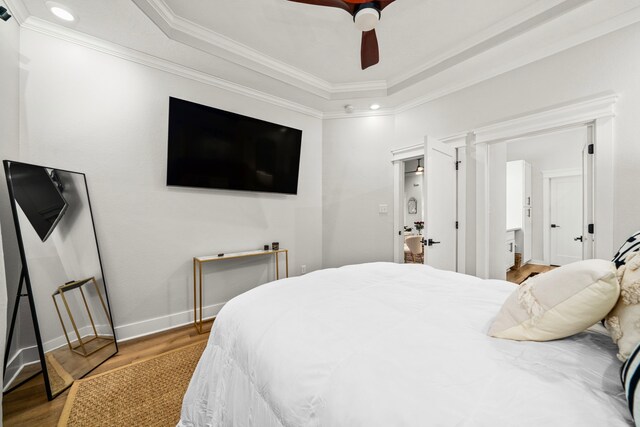 bedroom with recessed lighting, a tray ceiling, wood finished floors, ornamental molding, and baseboards