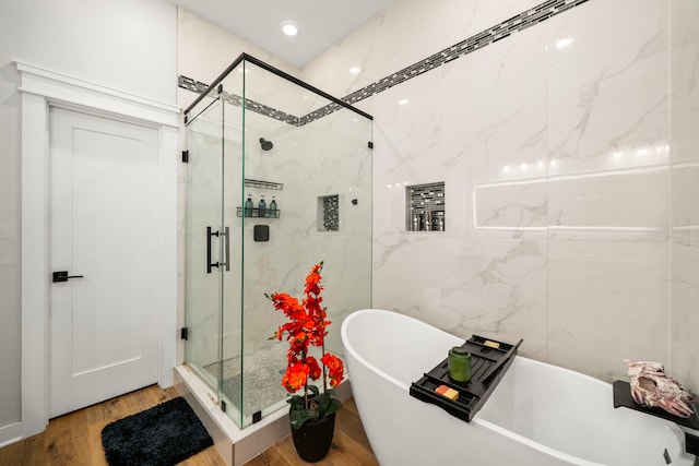bathroom with a soaking tub, wood finished floors, and a marble finish shower