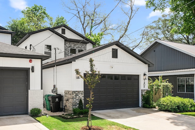 modern inspired farmhouse with a garage, stone siding, concrete driveway, and an outdoor structure