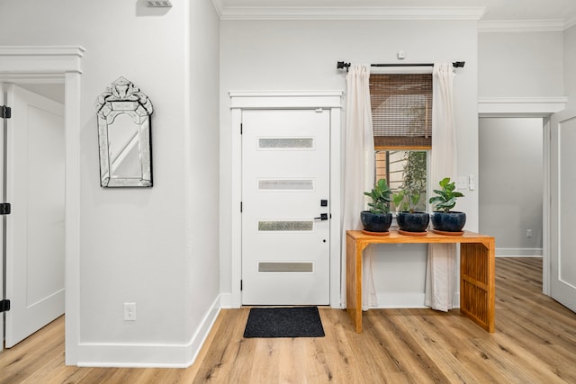 entryway featuring baseboards, crown molding, and light wood finished floors