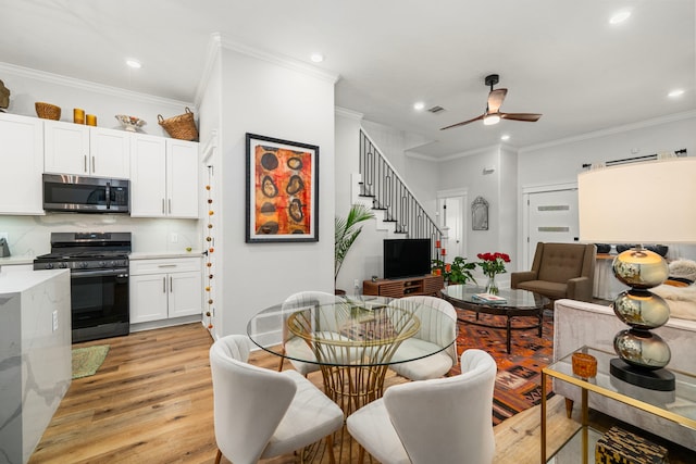 dining space featuring light wood-style flooring, recessed lighting, a ceiling fan, stairway, and crown molding
