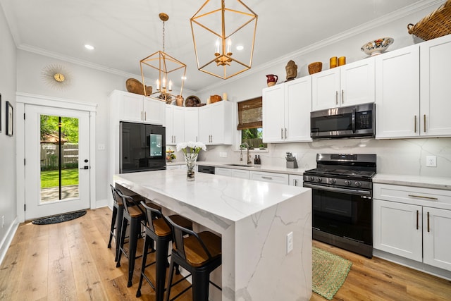 kitchen featuring stainless steel appliances, a sink, a kitchen island, and a healthy amount of sunlight