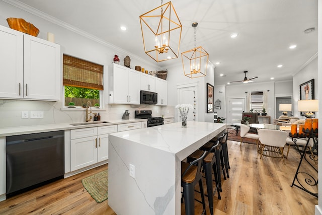 kitchen featuring dishwasher, ornamental molding, a sink, a kitchen island, and gas range