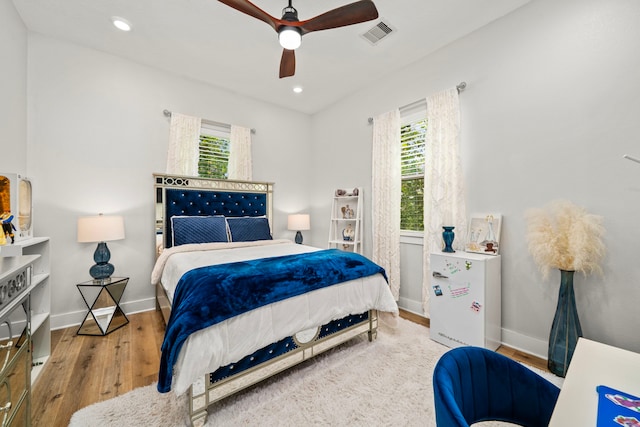 bedroom featuring wood finished floors, visible vents, baseboards, and multiple windows
