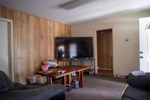 carpeted living area featuring wood walls