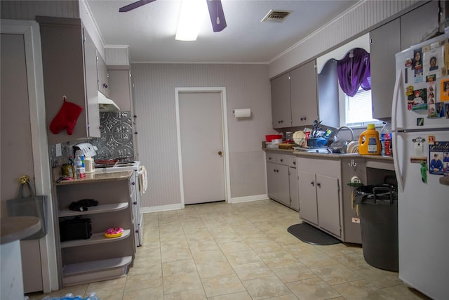 kitchen with under cabinet range hood, visible vents, a ceiling fan, white appliances, and crown molding