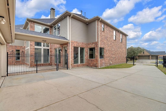 13811 Sugar Dock Ct, Houston, TX 77044 - rear view of house with a chimney, brick siding, a gate, concrete driveway, and a patio area