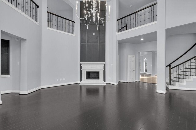 13811 Sugar Dock Ct, Houston, TX 77044 - unfurnished living room featuring a towering ceiling, stairway, a chandelier, wood finished floors, and a fireplace