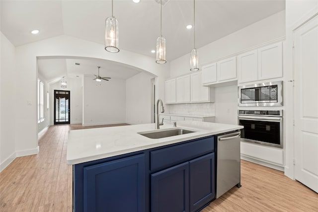 18402 Mesquite Flats Trl, Cypress, TX 77433 - kitchen featuring stainless steel appliances, a sink, vaulted ceiling, blue cabinetry, and white cabinets
