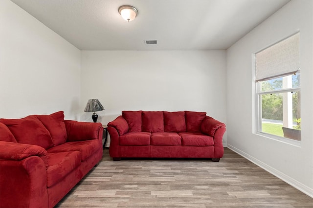 living room with wood finished floors, visible vents, and baseboards