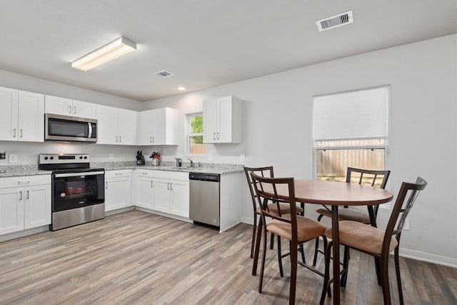 kitchen with light wood-style flooring, visible vents, and stainless steel appliances