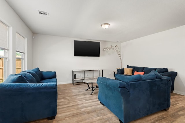 living room with light wood-style flooring, visible vents, and baseboards
