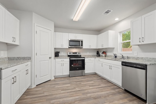 kitchen featuring light wood finished floors, visible vents, a sink, appliances with stainless steel finishes, and white cabinetry