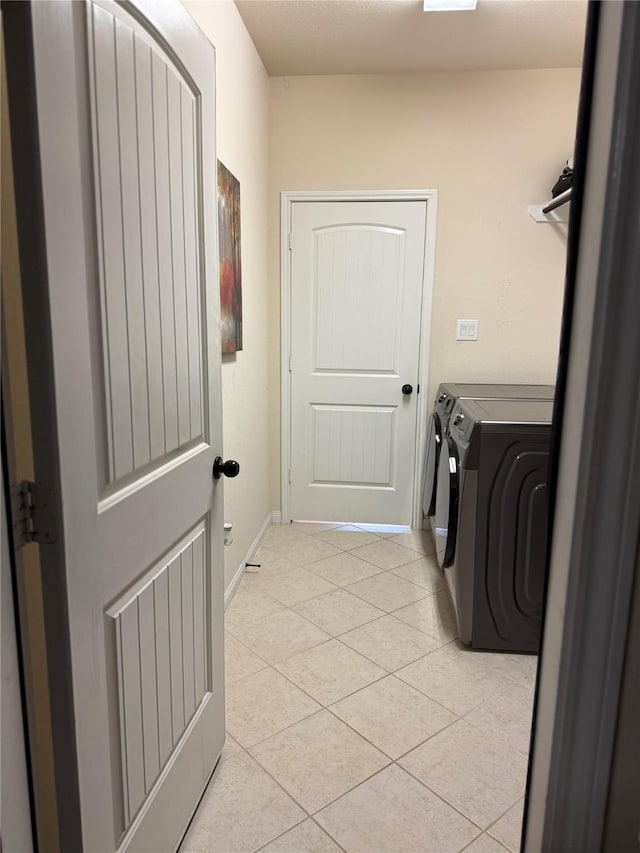 laundry room featuring baseboards, washing machine and clothes dryer, laundry area, and light tile patterned floors