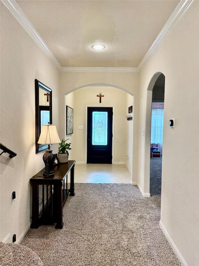 entryway with crown molding, tile patterned floors, arched walkways, carpet, and baseboards