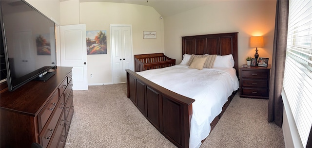 bedroom featuring vaulted ceiling, a closet, and light colored carpet
