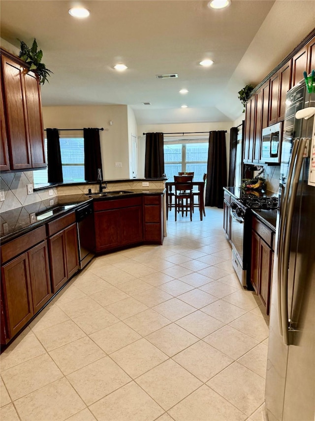 kitchen featuring dark countertops, tasteful backsplash, a sink, appliances with stainless steel finishes, and visible vents