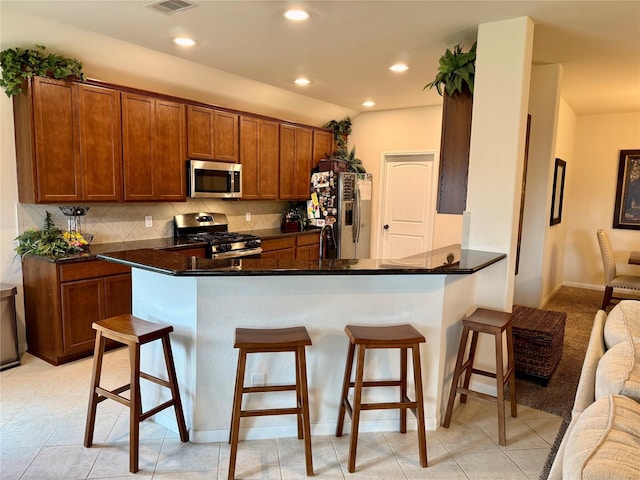 kitchen with decorative backsplash, open floor plan, stainless steel appliances, and a breakfast bar area