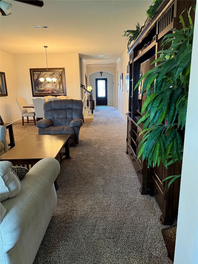 hall with carpet flooring, arched walkways, visible vents, baseboards, and a chandelier