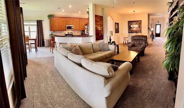 living area with light colored carpet, arched walkways, recessed lighting, and an inviting chandelier